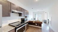 Located at 16790 Chandler Rd in East Lansing, Michigan, this efficiently designed one-bedroom, one-bathroom unit offers a thoughtful layout across a single floor. The open-concept kitchen and living area forms the heart of the space, featuring rich dark-toned shaker cabinetry, granite countertops, white subway tile backsplash, and a full suite of stainless steel appliances including a range, refrigerator, microwave, and dishwasher. Light wood-style flooring runs throughout the main living area, contributing to a bright and clean aesthetic. Sliding glass doors at the far end of the living area allow natural light to flow in and provide outdoor access. The bedroom is a cozy, well-defined retreat with neutral carpet flooring and a window that brings in additional natural light. The full bathroom is designed with accessibility in mind, featuring ADA-compliant grab bars, a wide open layout, wood-look tile flooring, a granite vanity, and a deep soaking tub. A dedicated in-unit laundry area houses a Whirlpool front-loading washer and dryer alongside overhead shelving for added storage. Clean white walls and recessed lighting throughout give the space a modern, well-maintained feel.