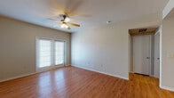 Located at 3200 Bromley Pl in Midland, Texas, this single-floor residence offers a well-organized layout with a variety of functional living spaces. The main living area is a standout feature, showcasing warm hardwood-style flooring that extends throughout the common areas, complemented by a ceiling fan with light fixture and a set of French doors that invite natural light and provide outdoor access. Neutral-toned walls throughout create a clean, versatile backdrop.

The kitchen is designed for practicality, featuring warm wood cabinetry, granite-style countertops, and black appliances including a refrigerator and range. A built-in desk or breakfast counter area adds extra functionality, while a pass-through opening connects the kitchen to the adjacent living and dining space, enhancing the open feel of the floor plan.

The bedrooms are finished with plush carpeting, ceiling fans, and windows that bring in natural light, offering comfortable and quiet retreats. The bathroom includes a full tub and shower combination with white tile surround accented by a bold black tile border, hardwood-style flooring, and clean chrome fixtures. The overall ambiance of this home is practical and move-in ready, with consistent finishes that lend a cohesive, well-maintained character throughout.