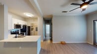 This single-story, two-bedroom, one-bathroom unit in Baton Rouge, Louisiana offers a well-designed open-concept layout that connects the living area and kitchen seamlessly. The living space features wood-style flooring, crown molding, and a ceiling fan, creating a comfortable and cohesive atmosphere. A peninsula-style kitchen island with a white countertop serves as a natural divider between the living and kitchen areas, providing additional workspace and casual seating potential.

The kitchen is well-equipped with stainless steel appliances, including a refrigerator, electric range, and built-in microwave. White shaker-style cabinetry with matte black hardware extends to the ceiling, complemented by a light blue subway tile backsplash that adds a subtle modern touch. Wood-style flooring continues throughout the kitchen.

The two bedrooms are carpeted and receive natural light through double windows fitted with blinds, offering outdoor views. Each room includes a ceiling fan for added comfort. The bathroom features a white vanity with shaker-style cabinetry, a tub-shower combination with tile surround, wood-style flooring, and a large mirror. An in-unit laundry area is also present, adding everyday convenience to this efficiently designed Baton Rouge residence.