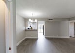 Located at 3901 36th Ct in West Palm Beach, Florida, this single-story home offers a thoughtfully updated interior with a clean, modern aesthetic. Wood-look tile flooring runs consistently throughout the living areas and bedrooms, providing both durability and visual warmth. Neutral gray walls and crisp white trim create a bright, cohesive palette across the entire home.

The open living and dining area is anchored by a contemporary multi-light chandelier and features a textured ceiling finish. A pass-through counter connects the dining space to the kitchen, enhancing the open flow. The kitchen is well-appointed with white shaker-style cabinetry, light countertops, a black electric range, and a stainless steel sink. A stacked Whirlpool washer and dryer unit is conveniently integrated into the kitchen space.

The bedrooms are generously proportioned, each featuring wood-look tile flooring, neutral walls, and windows with blinds that allow for natural light. The bathrooms are finished with marble-look tile, including a full bath with a tub-shower combination adorned with decorative mosaic tile accents, and a separate shower with floor-to-ceiling marble-look tile and a built-in niche. Sliding glass doors lead to an outdoor area, adding to the home's appeal in the sunny South Florida climate.