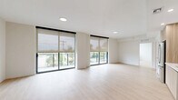 Located at 3411 N Federal Hwy in Fort Lauderdale, FL, this modern 2-bedroom, 2-bathroom residence offers a clean, contemporary design with a bright and airy atmosphere throughout. Light wood-tone flooring flows seamlessly across the entire single-floor layout, creating a cohesive and welcoming feel.

The open-concept living area is a standout, featuring expansive floor-to-ceiling sliding glass doors fitted with roller shades that invite abundant natural light while framing outdoor views of the surrounding Fort Lauderdale landscape. Recessed lighting complements the natural light throughout.

The kitchen is thoughtfully designed with two-tone cabinetry — combining warm wood lower cabinets with crisp white upper cabinets — paired with a light countertop, glass tile backsplash, and a full suite of stainless steel appliances including a refrigerator, range, microwave, and dishwasher. A stacked washer and dryer unit is conveniently located just off the kitchen.

Both bedrooms are well-proportioned with clean white walls and the same warm wood flooring, providing a calm, neutral canvas. The primary bedroom includes a spacious walk-in closet with wire shelving. Each of the two bathrooms features wood-toned vanity cabinetry, a white countertop, and a large mirror with overhead lighting.