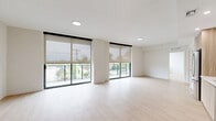 Located at 3411 N Federal Hwy in Fort Lauderdale, FL, this modern 2-bedroom, 2-bathroom residence offers a clean, contemporary design with a bright and airy atmosphere throughout. Light wood-tone flooring flows seamlessly across the entire single-floor layout, creating a cohesive and welcoming feel.

The open-concept living area is a standout, featuring expansive floor-to-ceiling sliding glass doors fitted with roller shades that invite abundant natural light while framing outdoor views of the surrounding Fort Lauderdale landscape. Recessed lighting complements the natural light throughout.

The kitchen is thoughtfully designed with two-tone cabinetry — combining warm wood lower cabinets with crisp white upper cabinets — paired with a light countertop, glass tile backsplash, and a full suite of stainless steel appliances including a refrigerator, range, microwave, and dishwasher. A stacked washer and dryer unit is conveniently located just off the kitchen.

Both bedrooms are well-proportioned with clean white walls and the same warm wood flooring, providing a calm, neutral canvas. The primary bedroom includes a spacious walk-in closet with wire shelving. Each of the two bathrooms features wood-toned vanity cabinetry, a white countertop, and a large mirror with overhead lighting.