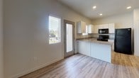 This single-floor residence offers a clean, modern design with a thoughtful layout that maximizes comfort and functionality. The open-concept living area is anchored by light wood-look flooring and recessed lighting, creating a bright and welcoming atmosphere. Neutral white walls throughout the space lend a fresh, versatile backdrop.

The kitchen is well-equipped with white cabinetry, granite-look countertops, a double-basin sink, and black appliances including a range, microwave, and refrigerator. A full-length glass panel door and a window provide natural light and outdoor views, further enhancing the airy feel of the space.

The bedrooms feature soft wall-to-wall carpeting and are bathed in natural light from multiple windows fitted with blinds. One bedroom includes a ceiling fan and corner windows, while another benefits from a spacious walk-in closet with built-in shelving and hanging rods.

Both bathrooms are finished with tile flooring, white vanities topped with granite-look counters, and full tub-shower combinations. A dedicated utility room houses the washer and dryer alongside the HVAC and water heating systems, keeping all essentials conveniently in one place. Overall, the space presents a practical and polished living environment.