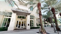 City Palms is a modern residential building distinguished by its clean, contemporary coastal architecture. The building's exterior is finished in a crisp cream and white facade, accented by teal-framed windows and decorative louvered shutters that lend a tropical, resort-inspired aesthetic. Mature palm trees line the entrance at 480, creating a lush, welcoming approach to the glass-paneled lobby doors beneath a structured overhead canopy. The ground-level entrance is well-defined, featuring clear signage and a polished, accessible entryway that reflects the building's attention to design detail.

The unit itself is contained on a single floor, offering a straightforward, efficient layout. While interior images are limited in visibility, the unit is part of a well-maintained, architecturally cohesive building that presents strong curb appeal and a distinct sense of place. The surrounding landscaping, including manicured greenery and towering palms, contributes to an overall ambiance that feels both urban and tropical. The building's multi-story design provides context for the scale and community environment in which this single-floor unit resides.
