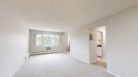 Located at 1365 N Western Ave in Saint Paul, Minnesota, this single-floor unit offers three bedrooms, one bathroom, a kitchen, and a hallway, making efficient use of its well-organized layout. The bedrooms are carpeted and neutral-toned, each equipped with ceiling fans and baseboard heating for year-round comfort. The spacious primary bedroom features two windows with vertical blinds that allow ample natural light, a window air conditioning unit, and a mirrored sliding closet door that enhances the sense of space. The additional bedrooms are similarly carpeted with ceiling fans and windows overlooking greenery outside. The galley-style kitchen is outfitted with white cabinetry featuring brass hardware, dark countertops with a double sink, tile flooring, and white appliances including an electric range and refrigerator. A doorway from the kitchen provides direct access to the bathroom. The bathroom is clean and functional, featuring white square wall tiles surrounding a tub-shower combination, small mosaic tile flooring, a toilet, and a warm wood-toned vanity with under-sink storage. The hallway connects the main areas of the unit efficiently. Overall, the space presents a practical and comfortable residential layout with consistent neutral finishes throughout.