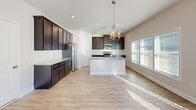 Located at 990 Perth Rd in Mooresville, NC, this two-story home offers a thoughtfully designed layout with contemporary finishes throughout. The main level features an open-concept kitchen equipped with dark espresso shaker-style cabinetry, granite countertops, a central island with pendant lighting, stainless steel appliances including a side-by-side refrigerator, and a classic subway tile backsplash. Light wood-look flooring flows through the main living areas, complementing the neutral color palette. The living area is generously sized, bathed in natural light from multiple windows, and features a ceiling fan overhead. A door leads directly to the exterior, enhancing connectivity to the outdoors. A powder room on the main level includes a pedestal sink and an oval mirror, adding a refined touch. The staircase connects to the upper level, where carpeted bedrooms provide comfort and quiet. Each bedroom benefits from large windows fitted with blinds, allowing ample natural light while maintaining privacy. A full bathroom upstairs includes a tub-shower combination with built-in shelving and light wood-look flooring. The home's clean, neutral tones and modern fixtures create a bright, move-in-ready environment throughout.