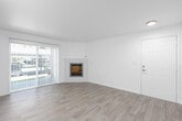 This well-appointed single-floor residence offers a clean, modern aesthetic with thoughtfully updated finishes throughout. The living room serves as the heart of the home, featuring durable wood-look flooring, a built-in fireplace with a white surround, and a sliding glass door fitted with vertical blinds that invite natural light and provide direct outdoor access. Adjacent to the living area, the dining space is highlighted by a elegant chandelier and flows seamlessly into the kitchen via a peninsula with a pass-through arch detail. The kitchen is efficiently designed with white cabinetry, black hardware accents, light wood-look flooring, white countertops, and a full suite of stainless steel appliances including a refrigerator, dishwasher, and range. Two bedrooms offer plush carpeting, ample natural light from well-placed windows with blinds, and built-in heating vents. The primary bathroom features wood-look tile flooring, a white vanity, and a glass-panel shower enclosure. The second bathroom is finished with a decorative patterned tile floor, a white vanity with a mirror, and a tub-shower combination. Throughout the space, a neutral white palette and consistent finishes create a cohesive, move-in-ready environment.