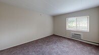 Located at 7200 Merion Trce in Upper Darby, PA, this two-bedroom, one-bathroom residence offers a practical and comfortable single-floor layout. The galley-style kitchen is well-appointed with gray cabinetry, a marble-look tile backsplash, dark countertops, and white appliances including an electric range and refrigerator. Light wood-look flooring in the kitchen transitions to plush carpeting throughout the living and bedroom areas, lending a warm, residential feel. The spacious primary bedroom features a large window that invites natural light and greenery views, along with a baseboard heating unit and a wall-mounted air conditioning unit for year-round comfort. The second bedroom offers generous proportions with soft carpet and easy access to the main living areas. The living area opens through sliding glass doors to a private balcony overlooking lush outdoor greenery, creating a bright and airy ambiance. The full bathroom is finished with marble-style tile flooring, a white vanity with storage cabinetry, and a shower-tub combination with a clean white curtain. Baseboard heating is found throughout the unit, ensuring efficient warmth during cooler months. This residence provides a straightforward, functional layout well-suited for comfortable everyday living.