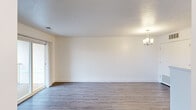 This thoughtfully laid-out 1-bedroom, 1-bathroom unit offers a clean, modern aesthetic throughout its single floor. The open-concept living room and kitchen area is anchored by durable wood-style flooring, crisp white walls, and a stylish chandelier that adds a refined touch. A sliding glass door floods the living space with natural light and provides access to an outdoor area with exterior views.

The galley-style kitchen is well-appointed with white shaker cabinetry, stainless steel appliances including a refrigerator and range, a built-in dishwasher, and a stainless steel sink — all set against bright white countertops. An in-unit washer hookup is also conveniently located just off the kitchen.

The bedroom offers a comfortable and quiet retreat, featuring plush carpeting, neutral tones, and two closets that provide generous storage. The full bathroom includes a tub and shower combination with a curved curtain rod and clean white finishes.

Throughout the unit, the consistent use of light colors, wood-style flooring in the main areas, and carpet in the bedroom creates a cohesive and inviting atmosphere. The efficient, functional layout makes excellent use of the available space, making this a practical and comfortable home.