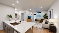 This thoughtfully designed one-bedroom, one-bathroom residence offers an efficient and modern layout across a single floor. The open-concept kitchen and living area serves as the heart of the home, anchored by a generous quartz-topped island with an undermount sink and seating for multiple stools — ideal for casual dining or entertaining. The kitchen features tall gray shaker-style cabinetry, stainless steel appliances including a full-size refrigerator and built-in microwave, and recessed lighting throughout. Light hardwood flooring flows seamlessly from the kitchen into the living area, which is bright and welcoming with a large window that brings in natural light and views of the surrounding neighborhood. The bedroom offers a comfortable, serene retreat with direct access to a dedicated closet with built-in shelving. The full bathroom is finished with clean, neutral tones, featuring a tub-shower combination with brushed nickel fixtures, a gray vanity with white countertop, and wood-look flooring. A in-unit laundry closet houses a full-size washer and dryer with overhead shelving for storage. Recessed lighting and a crisp white color palette create a bright, modern ambiance throughout the entire space.