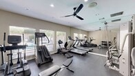 Located at 5525 N Stanton St in El Paso, Texas, this fitness center offers a comprehensive and well-organized exercise facility designed to support a full range of workout routines. The single-room space is finished with durable dark rubber flooring, smooth neutral-toned walls, and a white ceiling fitted with recessed lighting and a ceiling fan that promotes airflow and comfort during workouts.

Natural light flows in through multiple windows fitted with horizontal blinds, offering views of the surrounding outdoor greenery and creating an inviting atmosphere. Full-length wall mirrors run along a significant portion of the room, visually expanding the space and allowing users to monitor their form during exercise.

The cardio section is well-stocked with multiple treadmills, an elliptical trainer, a stair climber, and a stationary bike. Strength training is supported by a multi-station cable and pulley machine, ideal for a variety of resistance exercises. A dedicated free weights area features a tiered dumbbell rack with a broad selection of weights and an accompanying bench. A glass-paneled door provides easy access to the facility. Overall, the space maintains a clean, functional aesthetic that prioritizes usability, making it a practical and fully equipped destination for daily fitness.