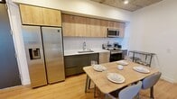This contemporary 780 square foot apartment, located at #831 TENTEN Downtown, offers a harmonious blend of style and functionality. The space comprises three bedrooms, including a 130 square foot primary bedroom, two bathrooms, and an open-concept kitchen and living area.

The kitchen showcases a modern design with sleek cabinetry in light wood and dark tones, complemented by stainless steel appliances and a convenient center island that doubles as a dining space. The living room features a minimalist aesthetic with a comfortable sofa, glass coffee table, and a vibrant yellow accent chair, creating a welcoming atmosphere.

The bedrooms are designed for comfort, with ample natural light and built-in storage solutions. The bathrooms boast a clean, modern look with glass shower enclosures, floating vanities, and LED-illuminated mirrors.

A standout feature is the balcony, offering breathtaking views of the surrounding cityscape and lush interior courtyard. The use of glass balustrades ensures unobstructed views while providing a seamless indoor-outdoor living experience.

Throughout the apartment, you'll find high ceilings with exposed concrete elements, hardwood flooring, and large windows that flood the space with natural light. The overall design aesthetic is clean and uncluttered, with a neutral color palette punctuated by occasional pops of color, creating a sophisticated urban oasis in the heart of downtown.