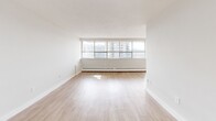Located at 65 Thorncliffe Park Dr in Toronto's Thorncliffe Park neighbourhood, this one-bedroom, one-bathroom unit offers a well-organized layout across a single floor. Light hardwood-style flooring runs throughout the main living areas, contributing to a clean, cohesive aesthetic.

The living room is generously proportioned, featuring a wide bank of floor-to-ceiling windows that flood the space with natural light and provide open views of the surrounding neighbourhood. Baseboard heating runs along the perimeter, and the room connects seamlessly to the private balcony, extending the living space outdoors.

The galley-style kitchen is efficiently designed with white shaker cabinetry lining both sides, granite-style countertops, stainless steel appliances including a refrigerator and electric range, and a stainless steel sink. A window at the end of the kitchen brings in additional natural light.

The bedroom is a comfortable size, featuring its own window, baseboard heating, and neutral walls that offer a calm, restful environment. The full bathroom is finished with large-format grey stone-look wall tiles surrounding the bathtub and shower combination, complemented by chrome fixtures. A hallway connects all areas of the unit, providing a practical and well-structured flow throughout the space.