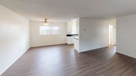 Located at 7980 Linda Vista in San Diego, Unit #28 is a single-floor residence that offers a clean, functional layout with a bright and neutral aesthetic throughout. The open living and dining area is finished with warm-toned wood-style flooring and features a ceiling fan with light fixture, a textured ceiling, and multiple windows dressed with vertical blinds that invite generous natural light into the space. A front entry door with an adjacent window further enhances the airy feel of the main living area. The galley-style kitchen is efficiently designed with white cabinetry, dark stone-style countertops, a double-basin sink, a dishwasher, a refrigerator, and a coil-top range, all set over matching wood-style flooring. The bedrooms are carpeted and offer a comfortable, quiet atmosphere, each featuring windows with views of the surrounding outdoor greenery. The bathroom is well-appointed with a wood-toned vanity, dark granite-style countertop, a single-basin sink, a full tub and shower combination, and a small high window that provides ventilation and light. Wood-style flooring in the bathroom complements the overall design continuity of the unit. The space presents a straightforward, move-in-ready interior suited for everyday living.