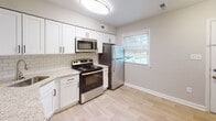 This two-story residence is thoughtfully laid out across two distinct levels connected by a staircase. The main level features an open-concept living area with light hardwood-style flooring and neutral gray walls, creating a clean, contemporary atmosphere. A sliding glass door floods the living space with natural light and provides outdoor access. The kitchen is well-equipped with white shaker-style cabinetry, granite-look countertops, a subway tile backsplash, and a full suite of stainless steel appliances including a refrigerator, range, microwave, and dishwasher. A breakfast bar connects the kitchen to the main living area, enhancing the open flow of the space.

The upper level is home to the bedrooms, each finished with plush carpeting, neutral-toned walls, and ceiling fans with integrated lighting. Bedrooms offer generous closet space, with at least one room featuring both a standard closet and an additional storage door. The bathroom includes a soaking tub and shower combination finished with classic white subway tile and chrome fixtures. Throughout the home, clean lines, consistent neutral tones, and updated finishes contribute to a cohesive and move-in-ready aesthetic.