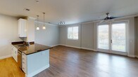 Located at 7084 Friars Road, Unit 301 in San Diego, this single-floor residence offers a thoughtfully designed layout with clean, modern finishes throughout. The entryway features a hallway with crown molding details and wood-style flooring that flows seamlessly into the main living areas, creating a cohesive and polished aesthetic.

The open-concept living and dining area is generously proportioned, benefiting from multiple windows fitted with horizontal blinds that allow ample natural light. Crown molding accents the ceilings, while a ceiling fan and track lighting provide functional illumination. A sliding glass door leads to an outdoor-facing area, further enhancing the sense of openness.

The kitchen is well-equipped with white shaker-style cabinetry, dark granite countertops, stainless steel appliances including a side-by-side refrigerator, electric range, and built-in microwave. Pendant lighting above the kitchen counter adds a refined touch.

Bedrooms offer a comfortable retreat; one features soft carpeting and a bright window with outdoor views, while another showcases wood-style flooring and a ceiling fan. Both bathrooms include white vanities with dark granite countertops and tub-shower combinations, maintaining a consistent, clean design throughout the unit.