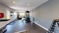 Located at 100 Pinegate Cir in Chapel Hill, NC, this fitness center offers a well-equipped exercise space designed to support a well-rounded workout routine. The room features a clean, functional layout with neutral gray walls, recessed ceiling lighting, and durable dark flooring that creates a practical and focused atmosphere throughout.

The cardio section is anchored by a row of T800 treadmills positioned along one wall, complemented by a stair climber and a stationary bike, providing ample options for aerobic training. A multi-station cable machine and a weight bench serve as the centerpiece for strength training, while a dumbbell rack lines one wall, offering a range of free weights. Additional accessories, including exercise balls and medicine balls, round out the functional fitness offerings.

Natural light filters in through several windows fitted with blinds, keeping the space bright without sacrificing privacy. A glass-paned entry door provides a welcoming entrance with a view of the surrounding greenery. Safety is addressed with a wall-mounted fire extinguisher near the exit. The space is efficiently organized to maximize usable floor area, making it accessible and easy to navigate for a variety of fitness activities.