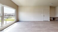 Located at 4007 N Ridge Rd in Wichita, Kansas, this single-floor, 3-bedroom, 2-bathroom home offers a well-designed layout with modern finishes throughout. The open-concept kitchen and living area serve as the heart of the home, featuring a large center island with a white quartz countertop, rich dark wood cabinetry, stainless steel refrigerator, and sleek pendant lighting. A sliding glass door off the kitchen opens to an outdoor deck, filling the space with natural light and providing easy access to exterior views of the surrounding community. The living room is bright and open, with light wood-look vinyl plank flooring and large windows that invite additional natural light. Each bedroom is carpeted for comfort and includes a closet, while the primary bedroom stands out with expansive windows offering community views. Both bathrooms are finished with warm wood-tone cabinetry, white countertops, and luxury vinyl plank flooring, with one bathroom featuring a tall storage tower for added functionality. A dedicated laundry room accommodates a full-size washer and dryer side-by-side, complete with overhead shelving. Neutral tones and clean lines throughout give the home a fresh, move-in-ready appeal.