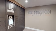 The Preste Miracle Mile presents a thoughtfully designed lobby and common area that combines functionality with clean, contemporary aesthetics. The entrance area immediately establishes the building's identity through prominent branded signage displayed on a warm taupe accent wall, complemented by recessed lighting and light-toned tile flooring that runs throughout the space.

A key feature of the lobby is the floor-to-ceiling automated package locker system, finished in dark charcoal and equipped with an interactive touchscreen terminal, offering residents a secure and convenient solution for parcel retrieval. Adjacent to this, a wall-mounted mailbox unit provides individual compartments for traditional mail delivery.

The elevator vestibule is clean and functional, featuring stainless steel elevator doors framed by neutral gray walls and accented by a distinctive slatted wood panel detail that adds warmth and texture to the otherwise minimalist corridor. A wall-mounted monitor displaying building information serves as a practical communication hub for residents.

Overall, the common areas of The Preste Miracle Mile reflect a modern residential aesthetic, balancing practical amenities with refined design details that create a welcoming and organized environment for residents.
