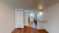 Located at 2514 W Hickory St in Denton, Texas, this single-floor unit offers a practical and straightforward layout designed for efficient living. The main living area greets you with warm wood-look flooring and a ceiling fan with integrated lighting, while a window allows natural light to fill the space. The entry transitions seamlessly between tile and wood-look flooring, creating a natural delineation between zones.

The kitchen is well-equipped with dark espresso-toned cabinetry, a stainless steel sink set into a laminate countertop, a white refrigerator, and an electric range. Light tile flooring runs throughout the kitchen area, and a pass-through counter connects the kitchen to the living space, enhancing the open feel.

An open shelving unit provides accessible storage near the kitchen transition area, while an additional door offers a separate entry or utility access. The HVAC system is served by wall vents and floor registers distributed throughout the unit.

The bathroom features tile wainscoting, a vanity with a white sink, a medicine cabinet with a mirror, wall-mounted light bar, and coordinating dark hardware throughout. The overall aesthetic is clean and functional, making this Denton property a straightforward and practical space.