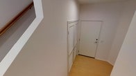 This well-designed space spans three floors, offering a versatile and functional layout throughout. The entryway sets the tone for the rest of the home with its clean, minimalist aesthetic. Light hardwood flooring runs through the entry area, creating a warm and inviting first impression. A solid white front door with a silver lever handle provides a secure and polished point of entry, while louvered bifold closet doors nearby offer convenient storage space — ideal for coats, shoes, or other essentials. The crisp white walls throughout the entryway reflect light effectively, contributing to a bright and airy atmosphere. A staircase with a warm wood handrail is visible from the entry, connecting the floors and reinforcing the multi-level nature of the space. The overall design language emphasizes simplicity and practicality, with clean lines and neutral tones that provide a versatile backdrop. The three-floor layout suggests ample space for a variety of uses, from living and dining areas to private retreats, making this a well-rounded and thoughtfully arranged property.