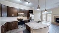 Located in Atlanta, GA, this well-appointed multi-level townhome offers five bedrooms, seven bathrooms, and a thoughtfully designed layout spread across four floors. The entry-level garage features a concrete floor, automatic door opener, and ample storage potential. The main living level showcases an open-concept kitchen and living room with soaring ceilings, crown molding, and a striking stone-surround fireplace with a raised hearth. The living area is bathed in natural light through large windows and glass French doors leading to an outdoor balcony. The kitchen is outfitted with dark wood cabinetry, granite countertops, a peninsula island with pendant lighting, subway tile backsplash, and stainless steel appliances. Hardwood-style flooring runs throughout the main living areas, while bedrooms feature plush carpeting. Each bathroom is finished with granite vanity tops, white cabinetry, and tub/shower combinations with clean white tile surrounds. The generously sized primary bedroom offers elevated ceilings and a ceiling fan. A dedicated closet, multiple hallways, and nine staircase segments connect the floors efficiently. Neutral warm tones and consistent finishes give the entire home a cohesive, move-in-ready aesthetic.