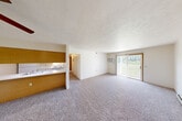 Located at 15881 McClellan Dr in Marshall, Michigan, this two-bedroom, one-bathroom single-story unit offers a functional and comfortable layout. The open-concept living and dining area is carpeted throughout, with a textured ceiling and a sliding glass door that opens to a private patio, allowing natural light and outdoor views to flow into the space. A wall-mounted air conditioning unit provides climate control in the main living area. The pass-through kitchen features white cabinetry with wood-tone trim, a stainless steel sink, electric range, refrigerator, and tile flooring, keeping it efficient and well-organized. The dining area connects seamlessly to the living space via a wood-paneled breakfast bar. The spacious primary bedroom includes a ceiling fan with light fixture, a window with outdoor views, a baseboard heater, and ample closet space. The second bedroom is similarly carpeted and bright, with its own closet. In total, four closets provide generous storage throughout the unit. The full bathroom features tile flooring, a single-sink vanity with a large mirror, a bathtub/shower combination, and a baseboard heater. A hallway connects all rooms efficiently, completing this well-laid-out and practical living space.