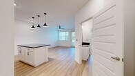 This thoughtfully designed one-bedroom, one-bathroom residence offers a bright and modern living experience across a single floor. The open-concept kitchen and living area forms the heart of the home, featuring light hardwood-style flooring that flows throughout the main living spaces. The kitchen is well-appointed with crisp white shaker cabinetry, dark granite countertops, a white subway tile backsplash, and a full suite of stainless steel appliances including a refrigerator, range, microwave, and dishwasher. A kitchen island provides additional counter space and casual seating. The living area is airy and inviting, with a ceiling fan overhead and a glass door that opens to a private balcony, allowing for generous natural light and outdoor views. The spacious bedroom is finished with plush carpeting, a large window overlooking greenery, and ample room for furnishings. A hallway connects the bedroom to the full bathroom, which features a tiled tub-shower combination. Clean white walls throughout the home create a fresh, neutral backdrop, while recessed lighting and modern fixtures add a polished, contemporary feel to the overall space.