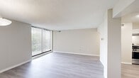 This well-appointed 3-bedroom, 1-bathroom unit is laid out entirely on a single floor, offering a clean and cohesive living environment with a neutral color palette throughout. The living room is a standout space, featuring light gray laminate flooring, a textured ceiling, and a large sliding glass door flanked by vertical blinds that opens to a balcony, flooding the room with natural light and offering outdoor views.

The kitchen is equipped with white shaker-style cabinetry, a white subway tile backsplash, stainless steel gas range, and a dishwasher, all set atop matching light laminate flooring. An adjacent dining area features a pendant light fixture and built-in closet, adding both function and charm.

Each of the three bedrooms is finished with plush neutral carpet and receives natural light through windows fitted with horizontal blinds. The primary bedroom offers a comfortable footprint ideal for a full bedroom suite. The shared bathroom is finished with square tile wainscoting, a white vanity with quartz-style countertop, a tri-light vanity fixture, a mirrored medicine cabinet, and a full shower-tub combination. A connecting hallway ties all rooms together, completing this efficient and thoughtfully designed floor plan.