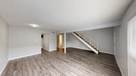 Located in Baton Rouge, Louisiana, this two-story, 2-bedroom, 1.5-bathroom home offers a well-organized layout with clean, modern finishes throughout. The main level features an open living area with durable wood-look laminate flooring in a cool gray tone, neutral light gray walls, and a textured ceiling. Natural light filters in through a front-facing window, brightening the expansive living space. A open staircase with a white metal railing connects the two floors, adding a structural focal point to the main level. The kitchen is equipped with dark shaker-style cabinetry, speckled laminate countertops, and an under-cabinet range hood, all set on light wood-look flooring. A convenient half bathroom on the main floor features a dark-toned vanity with a white countertop and mirror. Upstairs, two carpeted bedrooms provide comfortable retreats, each featuring mirrored sliding closet doors and windows with outdoor views. The full bathroom on the upper level includes a tub-shower combination, a dark vanity with a white countertop, and a large mirror. A hallway with additional closet space connects the upper-level rooms, completing this efficiently designed two-story home.