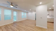 This well-appointed single-floor residence showcases a clean, contemporary design with an open-concept living and dining area at its heart. Light-toned luxury vinyl plank flooring flows throughout the main living spaces, complemented by crisp white walls, recessed lighting, and ceiling fans that enhance both comfort and style. Large windows dressed with blinds allow natural light to fill the rooms, creating a bright and welcoming ambiance.

The kitchen is a standout feature, equipped with light wood shaker-style cabinetry, granite countertops, a stainless steel refrigerator, a built-in double wall oven with microwave combo, a smooth cooktop, and a stainless steel range hood. A peninsula with pendant lighting provides additional prep space and casual seating, seamlessly connecting the kitchen to the living area.

The bedrooms are carpeted for added warmth and comfort, each featuring ceiling fans and generous natural light through large windows. One bedroom includes direct outdoor access. The primary suite is complemented by an en-suite bathroom with a walk-in glass-enclosed shower and a spacious walk-in closet with built-in shelving. A second full bathroom offers a granite vanity, light wood cabinetry, and a tub-shower combination. The overall aesthetic is modern, clean, and move-in ready.