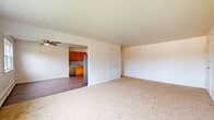 This two-bedroom, one-bathroom residence in Middletown, NY is thoughtfully laid out across a single floor, offering a comfortable and functional living environment. The open living room features neutral carpet flooring, a ceiling fan, and large windows that invite natural light and outdoor views, creating a bright and airy atmosphere. Baseboard heating runs throughout, ensuring year-round comfort. The kitchen is well-equipped with warm-toned wood cabinetry, granite-style countertops, a tile backsplash, stainless steel appliances including a gas range, dishwasher, and refrigerator, all set on durable hardwood-style flooring. A ceiling fan and window in the adjoining dining area add to the space's practicality. The primary bedroom is generously proportioned, featuring soft carpet, ample natural light from a large window, and multiple closet options. The second bedroom also offers carpeted flooring, a window with outdoor views, and baseboard heating. Six closets throughout the unit provide exceptional storage capacity. The full bathroom is finished with large-format neutral tile surrounding a soaking tub and shower, complemented by a white vanity. A hallway connects all rooms, contributing to a well-organized and efficient floor plan.