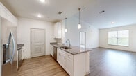 Located at 323 Seven Springs Way in Nashville, TN, this single-story, three-bedroom, two-bathroom residence offers a well-designed layout with modern finishes throughout. The open-concept kitchen and living area serves as the heart of the home, featuring a central island with granite countertops, an undermount sink, and elegant pendant lighting overhead. White shaker-style cabinetry, a subway tile backsplash, and stainless steel appliances — including a refrigerator, range, microwave, and dishwasher — complete the kitchen. Wood-style plank flooring runs through the main living areas, adding warmth and continuity to the space. The living room is bright and open, with direct sightlines to the kitchen and access to additional rooms. The bedrooms are carpeted and filled with natural light from large windows that offer views of surrounding greenery. The primary bedroom includes a spacious walk-in closet with wire shelving on three walls, providing generous storage. Two closets total serve the home's storage needs. The bathrooms are clean and functional, with one featuring a full tub-shower combination with brushed nickel fixtures and tile flooring. Vaulted ceilings in select areas enhance the sense of openness throughout this thoughtfully laid-out Nashville residence.