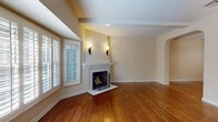 This two-story home combines classic architectural charm with functional design across both levels. The main living area serves as the centerpiece of the first floor, showcasing rich, warm-toned hardwood floors, a white-mantled brick fireplace, and elegant wall sconces that lend a welcoming ambiance. A bay window with plantation shutters floods the space with natural light, while a graceful staircase with wrought iron railings and a carpet runner connects the floors. An arched doorway adds a refined architectural detail to the open layout.

The kitchen is well-appointed with white cabinetry, granite countertops with a decorative tile backsplash, and a full suite of stainless steel appliances including a gas range, built-in microwave, and dishwasher. Hardwood flooring and a window with plantation shutters complete the space.

A half bathroom on the main level features a pedestal sink, hardwood flooring, and a large mirror. Upstairs, the bedrooms are generously sized with plush carpeting, crown molding, and window blinds that allow for natural light and privacy. One bedroom includes a built-in closet with shuttered doors and direct access to an outdoor balcony. A full bathroom upstairs offers a tiled vanity, soaking tub, and a window for ventilation.