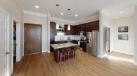 Located on 160th St W in Lakeville, Minnesota, this single-floor residence offers a thoughtfully designed layout with modern finishes throughout. The kitchen is a standout feature, showcasing rich dark cabinetry, granite countertops, a classic subway tile backsplash, and a full suite of stainless steel appliances including a range, microwave, and French door refrigerator. A granite-topped center island with bar seating and pendant lighting above creates an ideal space for both meal prep and casual dining. Light hardwood-style flooring flows throughout the main living areas, complementing the neutral gray walls and clean white trim. The living area benefits from natural light through large windows with vertical blinds, offering a bright and open atmosphere. The primary bathroom is generously proportioned, featuring a long dark-cabinet vanity with granite countertops, a large mirror with lighted fixture, and a glass-enclosed walk-in shower with tile surround and hardwood-style flooring. A second bathroom provides additional convenience with a tub-shower combo. Carpeted bedrooms offer a comfortable retreat, with windows providing natural light and exterior views. A dedicated in-unit laundry closet houses a full-size washer and dryer with overhead shelving for added storage.