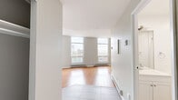 Located at 450 Rue Sherbrooke E in Montréal, this well-designed 1-bedroom, 1-bathroom unit offers a clean, modern aesthetic throughout its efficiently planned single-floor layout. The living room is a standout space, featuring warm hardwood flooring and an impressive arrangement of large windows that flood the room with natural light and frame open views of the surrounding Montréal cityscape. Baseboard heating runs along the perimeter, and the neutral grey walls complement the bright, airy atmosphere. The entry area transitions seamlessly from tile flooring into the hardwood of the main living space. The bedroom is a comfortable, well-proportioned room with its own window allowing natural light in, hardwood flooring, and a built-in closet with mirrored sliding doors offering practical storage. The bathroom is finished in a crisp, all-white palette with large-format beige tile flooring, a full-sized soaking tub with overhead shower, a vanity with under-cabinet storage, and recessed lighting. Throughout the unit, the consistent use of neutral tones, clean lines, and ample natural light creates a calm and functional living environment well-suited to urban living in the heart of Montréal.