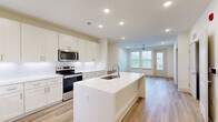 Located in Santa Rosa Beach, FL, this well-appointed one-bedroom, two-bathroom residence offers a thoughtfully designed single-floor layout with clean, modern finishes throughout. The open-concept kitchen and living area serves as the heart of the home, anchored by a central island with an integrated sink and white quartz countertops. The kitchen is equipped with stainless steel appliances — including a refrigerator, range, and microwave — complemented by white shaker-style cabinetry, a classic subway tile backsplash, and recessed lighting. Light-toned wood-look flooring flows seamlessly through the main living areas, enhancing the bright, airy ambiance. The living room features a ceiling fan and multiple windows with natural light and outdoor views. The primary bedroom is a comfortable, well-proportioned retreat with a ceiling fan, a window, and direct access to a walk-in closet outfitted with built-in wire shelving. The bathrooms are finished to a high standard, highlighted by a glass-enclosed walk-in shower with large-format tile, a built-in niche, and brushed gold fixtures. The overall design is cohesive and contemporary, with neutral tones and quality materials creating a clean, inviting atmosphere throughout.