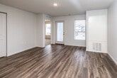 This single-floor unit offers a well-organized layout with a clear separation between living, sleeping, and utility spaces. The open-concept living and dining area features wood-look plank flooring that runs throughout the main areas, contributing to a cohesive and modern aesthetic. Large windows allow generous natural light to fill the space, with views of the surrounding community visible from multiple rooms.

The kitchen is equipped with dark-toned cabinetry, light countertops, and a peninsula that provides additional workspace and a natural divide from the living area. Black appliances include a refrigerator, range, microwave, and dishwasher. A dedicated laundry area with a stacked washer and dryer is conveniently accessible from the kitchen.

The bedrooms are carpeted and feature ceiling fans and windows that bring in ample daylight. The primary bedroom connects directly to a private bathroom equipped with a vanity featuring dark cabinetry, a sink, and a soaking tub. A second bathroom offers similar finishes with wood-look flooring, a single-sink vanity, and a separate shower area. The unit also includes closet storage and an exterior door leading to a private balcony from the living area.