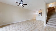 Located at 116 Champions Way in Davenport, Florida, this two-story home offers a well-designed layout that balances comfort and functionality. The main living area is generously sized and finished with light-toned tile flooring that runs throughout the common spaces, complemented by ceiling fans that promote airflow and comfort in the Florida climate. Vaulted ceilings in the living and dining areas add a sense of openness, and a sliding glass door provides direct access to the outdoor greenery beyond.

The kitchen is outfitted with dark espresso cabinetry, granite countertops, a decorative mosaic tile backsplash, and stainless steel appliances including a range and over-the-range microwave. Pendant lighting above the breakfast bar adds an inviting touch to this functional cooking space.

The bedrooms are carpeted for warmth and comfort, each featuring ceiling fans and natural light from windows with blinds. Storage is well-accounted for, with a spacious walk-in closet featuring wire shelving in the primary bedroom and additional closets with bi-fold doors in secondary bedrooms.

The bathroom showcases granite-topped dark wood vanities with undermount sinks, consistent with the home's cohesive design language. Light neutral tones throughout create a clean, bright ambiance well-suited to Florida living.
