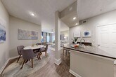 Located at 100 Lenox Park Cir NE in Brookhaven, GA, this one-bedroom, one-bathroom unit offers a thoughtfully designed single-floor layout with a neutral, modern aesthetic throughout. The open-concept living area seamlessly connects the kitchen, dining room, and living room, creating a spacious and functional flow. The kitchen features a peninsula with dark countertops, white cabinetry, a subway tile backsplash, and stainless steel appliances including a range, microwave, and refrigerator, all set on light wood-style flooring. The adjacent dining and living areas are well-lit with recessed lighting and benefit from natural light, with a sliding door providing access to a private balcony. The bedroom is carpeted and features a window allowing ample natural light. Three closets, including a generously sized walk-in, provide excellent storage. The bathroom includes a vanity with dark countertops, wood-style flooring, and a tub-shower combination. A dedicated in-unit laundry area adds everyday convenience. Textured ceilings and warm neutral tones carry throughout, giving the space a cohesive and comfortable feel. A hallway and entrance complete this well-appointed residence.