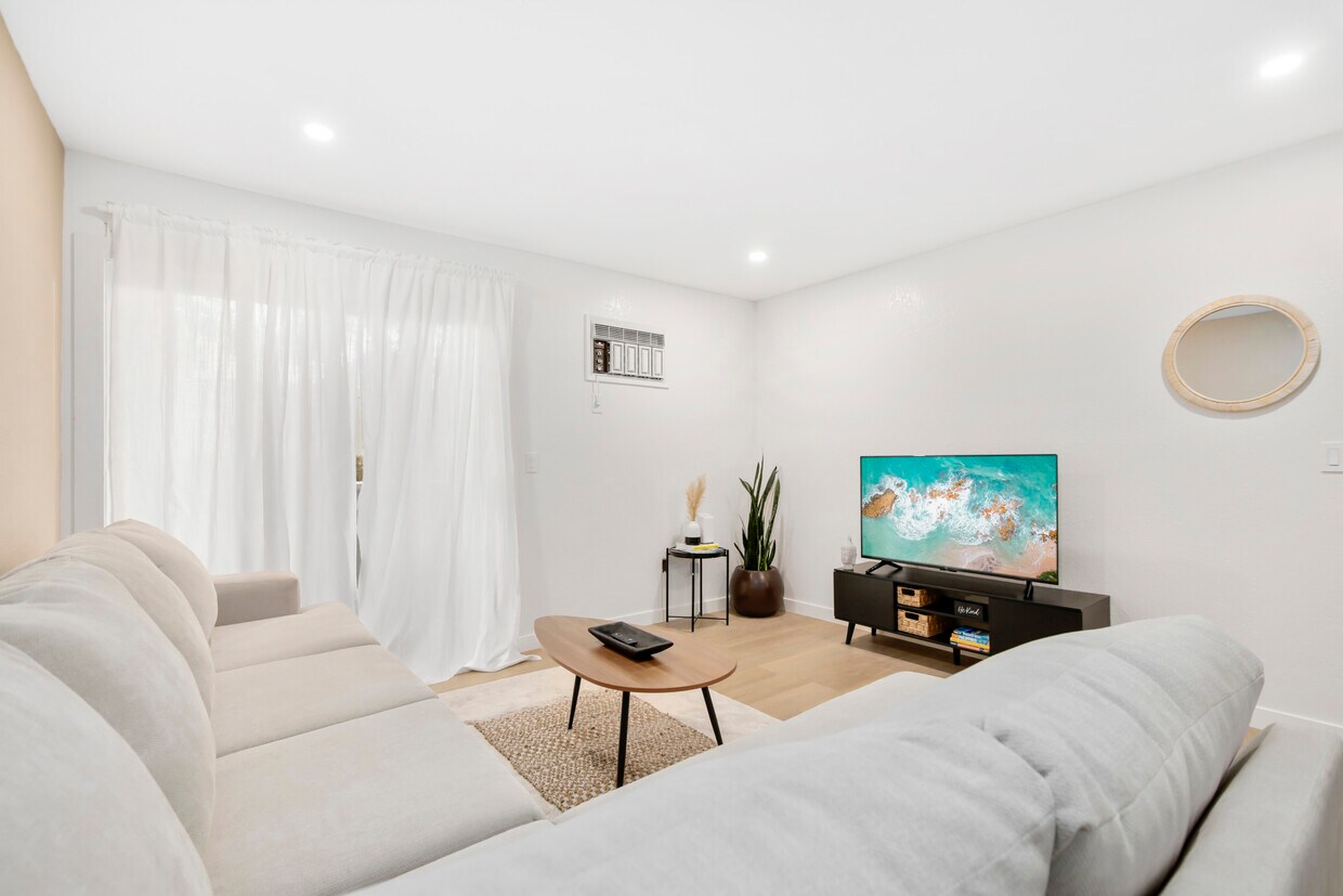 Bright living room with natural light, cozy seating, and smart TV – perfect for relaxing. - 1013 S Sunshine Ave
