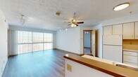This single-floor residence offers a functional and well-organized layout designed for comfortable everyday living. The open-concept kitchen and living area form the heart of the space, where wood-style laminate flooring, a ceiling fan with light fixture, and track lighting create a bright and practical atmosphere. The kitchen features white cabinetry, a peninsula with a laminate countertop, a white refrigerator, and an electric range, all arranged for efficient use of space. A large sliding glass door with vertical blinds in the living area fills the room with natural light and provides access to a private balcony with exterior views.

The bedrooms are carpeted for comfort and each includes a closet with built-in hanging rods. One bedroom features its own sliding glass door to a balcony, adding an additional outdoor connection. A dedicated walk-in storage closet with shelving provides generous organizational space. The bathroom includes a single vanity with a wide mirror and medicine cabinet, situated conveniently adjacent to the bedroom areas. A separate in-unit laundry room houses a washer and dryer alongside a water heater and wall-mounted shelving. Textured ceilings are consistent throughout, and the overall layout is efficient and practical.
