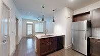 Located at 15923 Derby Rally in San Antonio, TX, this single-story, one-bedroom, one-bathroom residence offers a thoughtfully designed layout. The open-concept living and kitchen area is anchored by a central kitchen island featuring a granite countertop, undermount sink, and stylish pendant lighting. Rich dark-wood cabinetry lines the walls and pairs with a herringbone-patterned tile backsplash, stainless steel refrigerator, and black appliances including a range and built-in microwave. Wood-style flooring flows throughout the main living area, while a ceiling fan and large windows with blinds allow ample natural light to fill the space. A hallway leads to the bedroom, which is finished with soft carpeting, a ceiling fan, and a bright window. Two closets provide generous storage. The full bathroom is well-equipped with a granite-topped vanity with dark cabinetry, a tiled tub-shower combination, and wood-style flooring. Additional features include a pantry, in-unit laundry, and a private patio, making this a fully functional and efficiently organized home in the San Antonio area.
