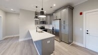 This single-floor residence in Lynchburg, Virginia offers a thoughtfully designed layout with modern finishes and a cohesive neutral color palette. The kitchen serves as a functional centerpiece, featuring gray shaker-style cabinetry with matte black hardware, crisp white countertops, stainless steel appliances, and a peninsula with an undermount sink and pendant lighting overhead. Light wood-look flooring runs throughout the main living areas, complementing the warm gray wall tones and white trim.

The living and dining areas are bright and open, with crown molding, ceiling fans, and recessed lighting adding refined detail. French doors in one room invite natural light and provide outdoor access. The bedrooms are carpeted for comfort, each equipped with ceiling fans and generous closet space, including a walk-in closet with dual hanging rods and built-in shelving.

The bathroom is finished with a gray vanity, white quartz countertop, a frameless mirror with contemporary sconce lighting, and marble-look tile flooring paired with a soaking tub and shower combination. Throughout the home, clean lines, consistent finishes, and a neutral palette create a polished, move-in-ready environment.