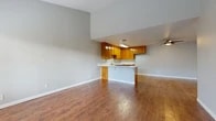 Located at 2880 W Ball Rd in Anaheim, California, this single-floor, 2-bedroom, 1-bathroom home offers a functional and comfortable layout. The open-concept living and dining area is anchored by warm hardwood-style flooring that extends throughout the main living spaces, creating a cohesive and inviting atmosphere. A large window in the living room floods the space with natural light, while a wall-mounted AC unit provides year-round climate control.

The kitchen is well-appointed with rich honey-toned oak cabinetry offering abundant storage, white countertops, a stainless steel sink, a dishwasher, and a gas range. A peninsula counter separates the kitchen from the living area, enhancing the open-plan feel. A ceiling fan overhead adds both style and function.

The two bedrooms feature plush carpeting, ceiling fans, and generous natural light from large windows with blinds. The primary bedroom is a comfortable size with vaulted ceilings and ample room for furnishings. A dedicated closet provides additional storage.

The bathroom is clean and functional, featuring a tub-shower combination with sliding glass doors, hardwood-style flooring, and a vanity with warm wood cabinetry. A window above the tub brings in natural light.