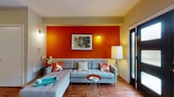 Located at 1361 Presidential Drive in Columbus, Ohio, this two-floor home makes a striking first impression with its bold, contemporary interior design. The main level opens into a welcoming living area anchored by a vivid burnt-orange accent wall, warm hardwood flooring, crown molding, and a ceiling fan. A set of sleek black double entry doors with glass panels floods the space with natural light and adds a modern architectural touch. The open layout flows seamlessly into a dedicated dining area and a galley-style kitchen, which features warm wood cabinetry, granite-look countertops, stainless steel appliances including a gas range and refrigerator, and continued hardwood flooring. The bathroom on the lower level is finished with clean white subway tile from floor to wainscot height, a classic pedestal sink, and a mirrored medicine cabinet. Upstairs, the bedroom is a bright and cheerful retreat highlighted by a bold yellow accent wall, plush carpeting, and windows that bring in ample natural light, accompanied by additional bathroom access. Throughout both floors, the home presents a cohesive and energetic design palette, balancing vibrant color with practical, well-appointed spaces ideal for comfortable everyday living.