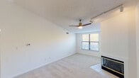 This well-appointed single-floor residence offers a clean, open layout bathed in natural light throughout. The living room serves as the heart of the home, featuring plush carpeting, a ceiling fan with integrated lighting, track lighting, and a sleek fireplace framed by tile surround — an inviting focal point for the space. A large window floods the room with natural light and offers views of surrounding greenery.

The layout flows seamlessly from the living area into a central hallway connecting the main rooms. The kitchen is equipped with white cabinetry, ample counter space, a full suite of white appliances including an electric range and built-in microwave, and wood-style flooring for easy maintenance.

The bedrooms are generously sized with soft carpeting, ceiling fans, and multiple windows that bring in abundant natural light and treetop views. The primary bedroom includes a walk-in closet and direct access to a full bathroom featuring tile flooring, a wide vanity with a granite-style countertop, a large mirror with Hollywood-style lighting, and a shower/tub combination.

A dedicated laundry area houses a full-size washer and dryer with overhead shelving for added storage. The overall aesthetic is bright, neutral, and move-in ready.