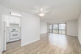 Located at 1000 S Catalina Ave in Redondo Beach, CA, this well-appointed one-bedroom, one-bathroom residence offers a bright and functional layout across a single floor. The open-concept living and dining area is a standout feature, finished with light wood-tone flooring and bathed in natural light from expansive sliding glass doors that open onto a private balcony with neighborhood views. A textured ceiling adds subtle character throughout the main living spaces. The kitchen is efficiently designed with white cabinetry, a pass-through counter connecting to the living area, and includes a full-size refrigerator and range. An adjacent built-in shelving nook provides additional storage and display space. The generously sized bedroom features plush carpeting, a large window with vertical blinds, and a mirrored sliding closet door that enhances the sense of space. A dedicated walk-in closet off the bedroom hallway offers dual clothing rods and ample shelving. The bathroom is accessed via a short hallway and includes a shower-tub combo with a glass enclosure. Clean white walls and a neutral palette throughout create a cohesive, move-in-ready environment well-suited to the relaxed coastal lifestyle of Redondo Beach.