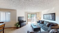 Located at 1544 Wessels Dr in Fort Wright, Kentucky, this single-floor residence offers a comfortable and functional layout across several well-defined living areas. The living room is generously proportioned, featuring plush wall-to-wall carpeting, a textured ceiling, and a sliding glass door that opens to a private balcony with pleasant outdoor views of mature trees. The room accommodates ample seating and provides a warm, inviting atmosphere. Adjacent to the living area, the dedicated dining space features classic wood wainscoting, subtle wallcovering, and a hanging pendant light above the dining table, with a window that brings in natural light. The kitchen is equipped with rich wood cabinetry, a full suite of appliances including an electric range, dishwasher, and refrigerator, along with generous counter space and a practical layout. The bedrooms are carpeted and well-lit, offering comfortable proportions with natural light filtering through vertical-blind-covered windows. The bathroom includes a full soaking tub and shower combination with decorative wall accents. Throughout the residence, textured ceilings and neutral wall tones create a cohesive, understated aesthetic that provides a versatile backdrop for personalization.
