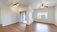 This single-floor residence offers a thoughtfully designed layout with a comfortable blend of style and functionality. The open living area features warm wood-look flooring, vaulted ceilings, and a ceiling fan, complemented by track lighting and a sliding glass door that leads to an enclosed space beyond. Natural light flows in through large windows fitted with horizontal blinds, offering views of the surrounding neighborhood.

The kitchen is outfitted with warm-toned wood cabinetry, dark countertops, and a full suite of appliances including an electric range, built-in microwave, and dishwasher, all set atop matching wood-look flooring.

The bedrooms are carpeted and generously sized, each receiving ample natural light through well-positioned windows. One bedroom features a walk-in closet with dual hanging rods providing extensive storage, while another includes a standard reach-in closet.

The primary bathroom is appointed with a dual-sink vanity set in dark countertops, warm wood cabinetry, hardwood-style flooring, and a large mirror with modern bar lighting. A secondary full bathroom includes a tub-shower combo, single-sink vanity with matching cabinetry, and a small window for ventilation and natural light. Throughout, the neutral color palette and clean finishes contribute to a bright, inviting atmosphere.